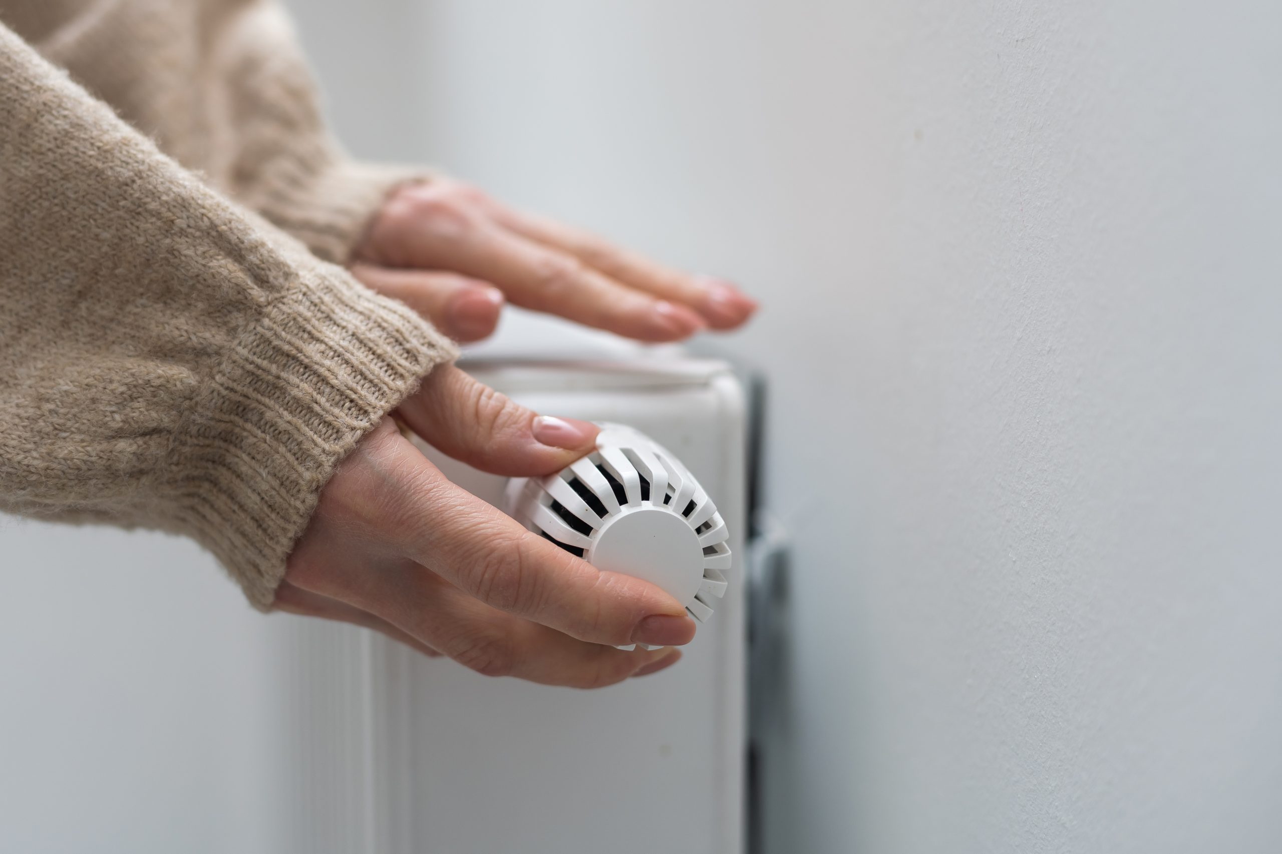 Woman holding temperature knob of heating radiator